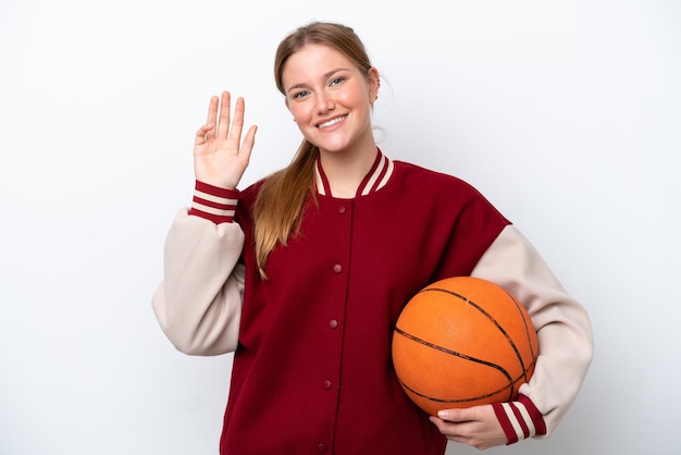 Young basketball player woman isolated on white background saluting with hand with happy expression