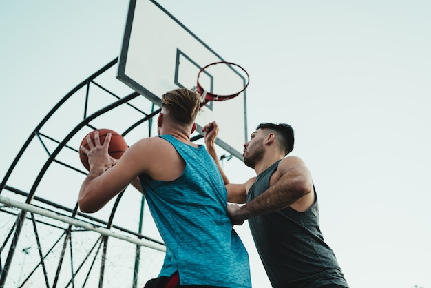 Young basketball players playing one-on-one on outdoor court. Sport and basketball concept.