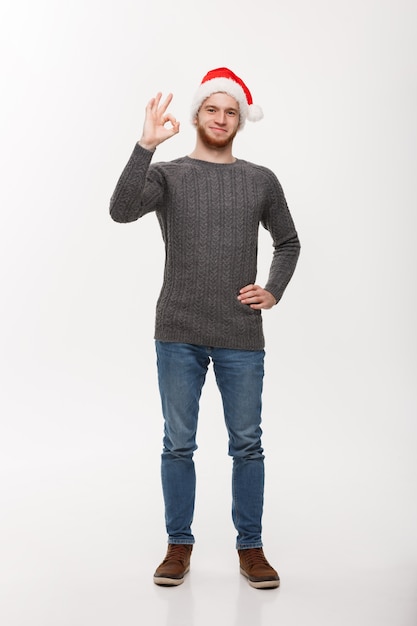 Young beard man in sweater giving ok sign to camera.