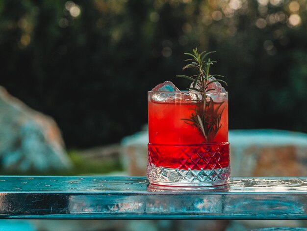 young bearded barman staff make red cocktail drink on decorated low glass outdoors in event