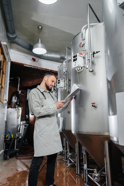 A young bearded brewer monitors the sensor readings during the brewing process