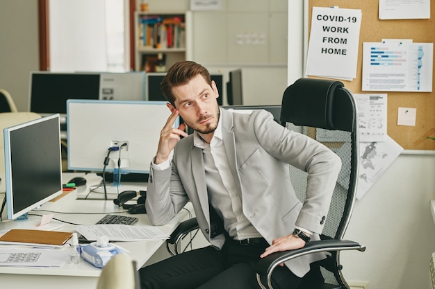 Photo young bearded businessman being upset about business problems sitting at desk