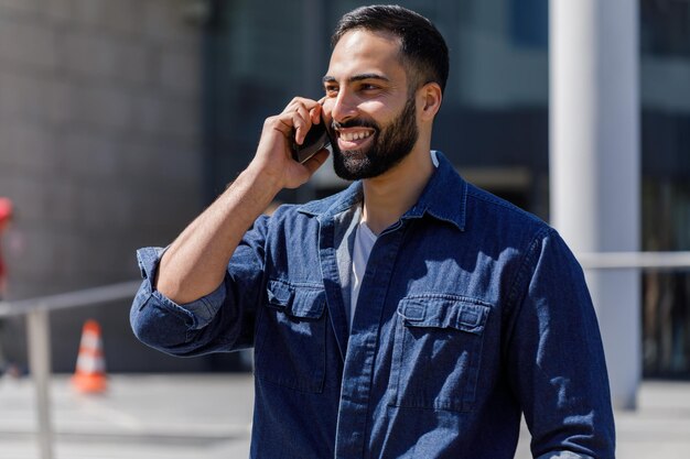 Young bearded businessman talking on his cellphone outdoors