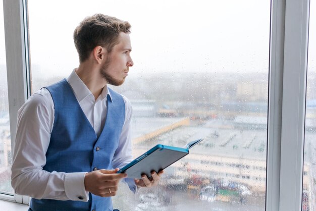 Young bearded businessman works in office takes notes in notebook analyzes