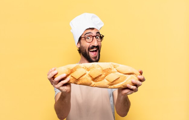 Young bearded chef man surprised expression holding a bread