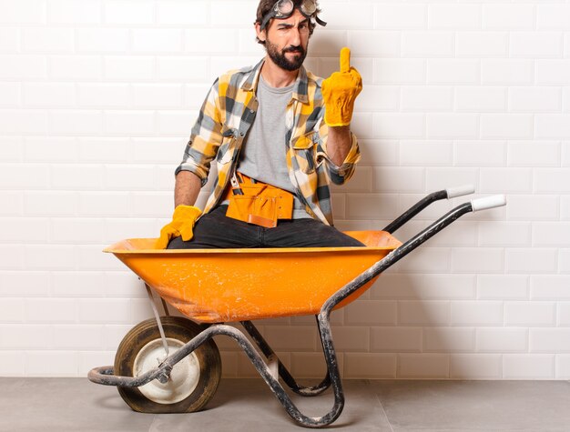 Young bearded construction worker man on a wheelbarrow