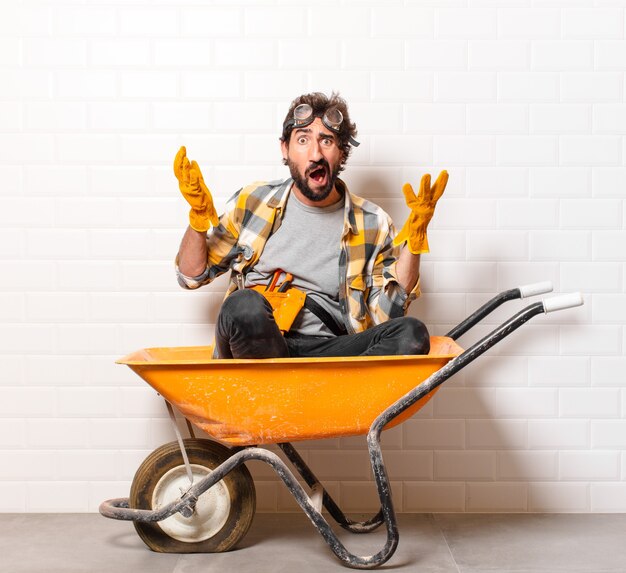 Young bearded construction worker man on a wheelbarrow