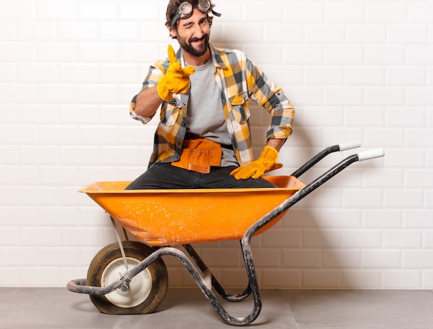Young bearded construction worker man on a wheelbarrow