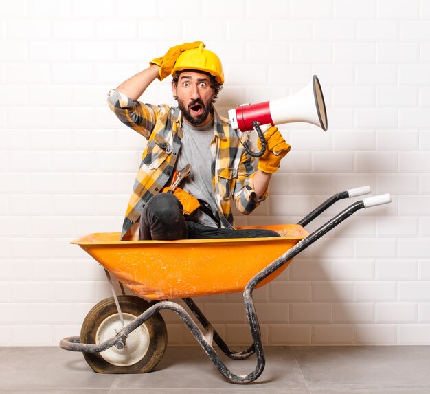 Photo young bearded construction worker man on a wheelbarrow