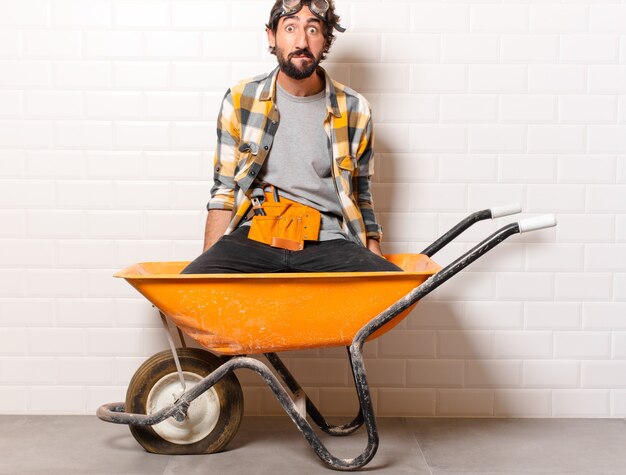 Young bearded construction worker man on a wheelbarrow