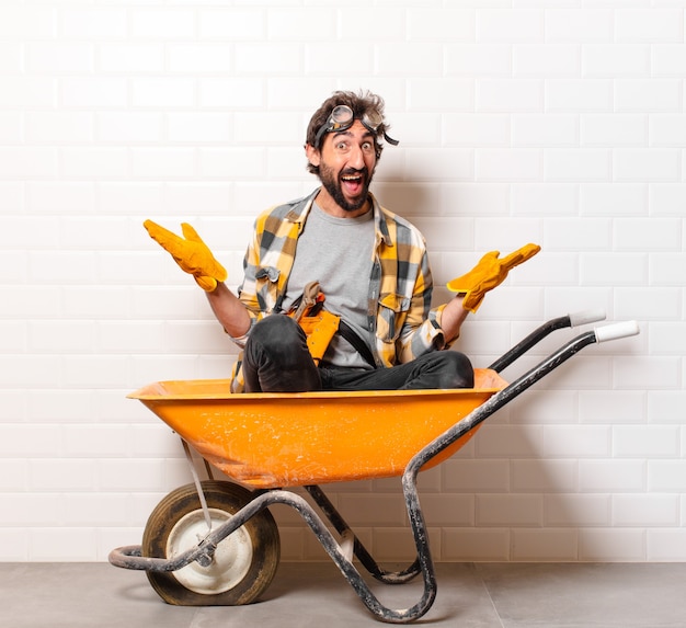 Young bearded construction worker man on a wheelbarrow