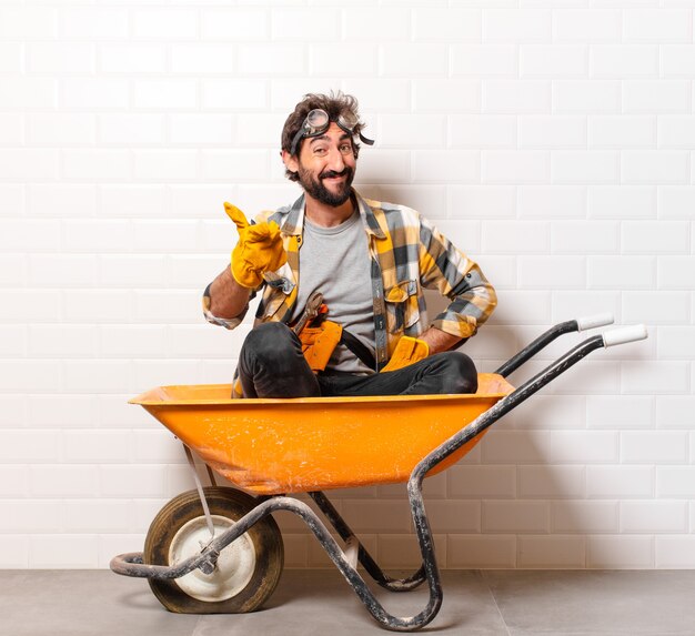 Young bearded construction worker man on a wheelbarrow