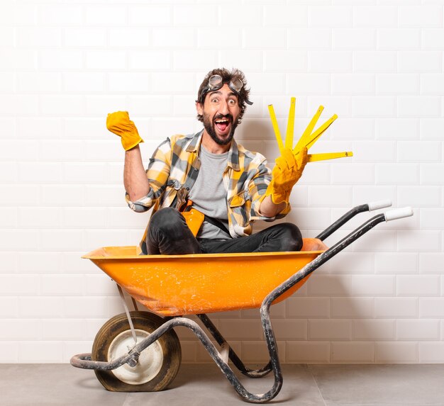 Young bearded construction worker man on a wheelbarrow