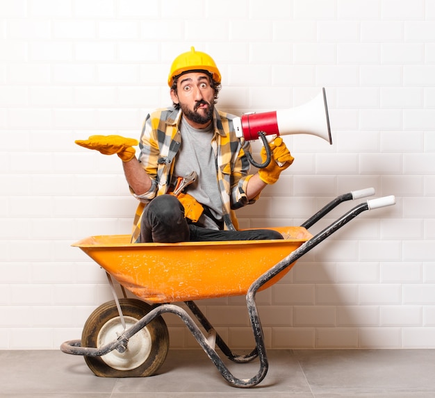 Young bearded construction worker man on a wheelbarrow