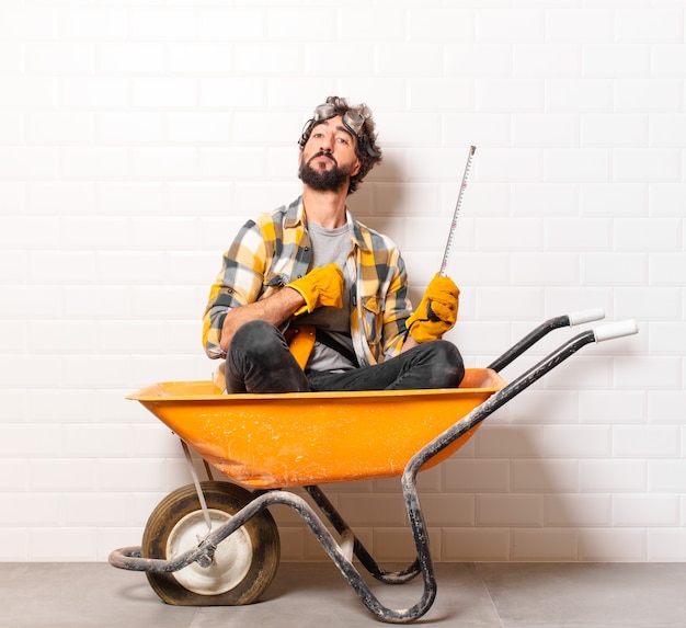 Young bearded construction worker man on a wheelbarrow