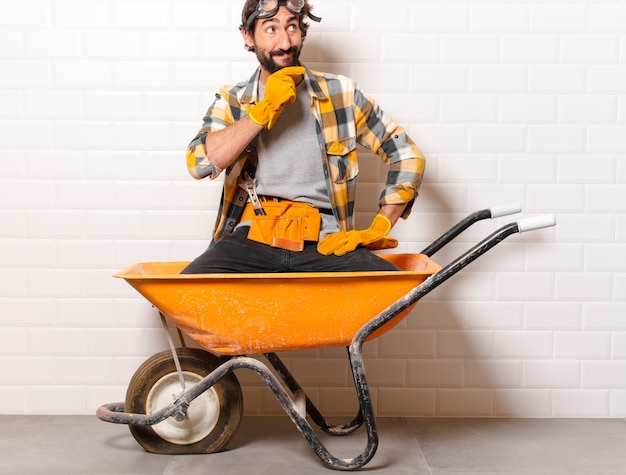 Young bearded construction worker man on a wheelbarrow