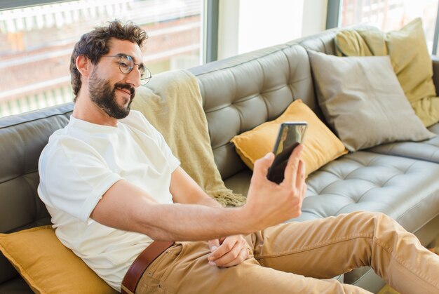 Young bearded cool man sitting on a couch at home