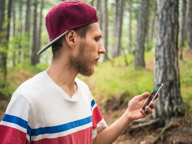 Young bearded hipster blogger make live stream in social network  walking in forest