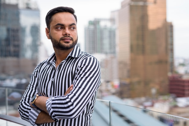 Young bearded Indian businessman against view of the city