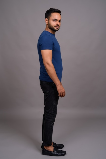 Young bearded Indian man against gray wall
