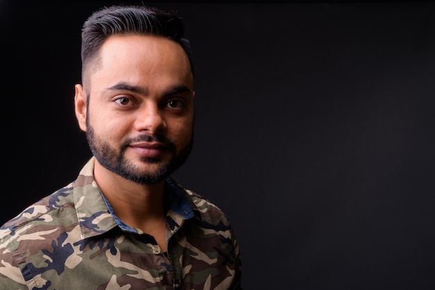 Young bearded Indian man against gray