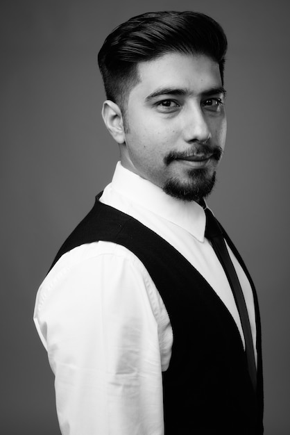  young bearded Iranian businessman against gray wall in black and white