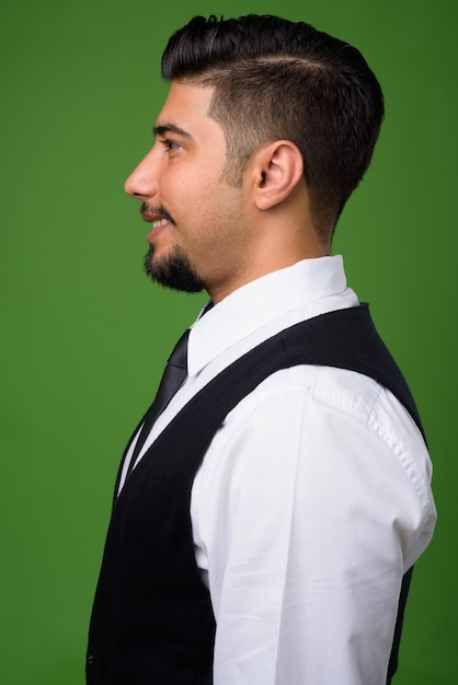 Young bearded Iranian businessman on green