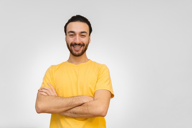 Young bearded latin and hispanic man looking at camera and smiling with crossed arms White background