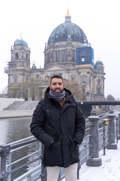 Young bearded male tourist happily having his picture taken with the Berlin Cathedral in the background