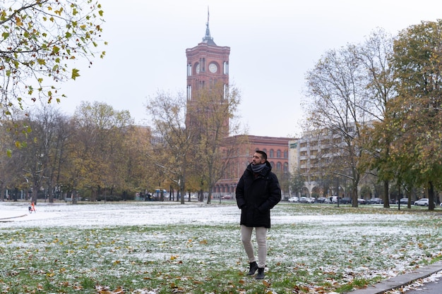 Young bearded male tourist with the Rotes Rathaus in the background and all snowed in