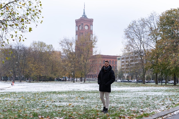 Young bearded male tourist with the Rotes Rathaus in the background and all snowed in