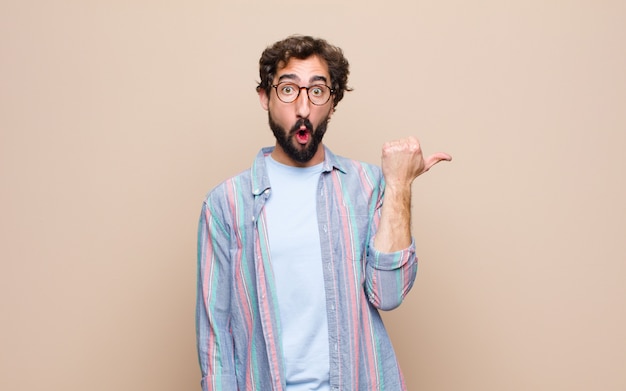 Young bearded man against flat wall