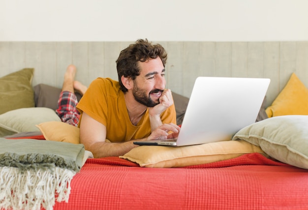 Young bearded man on a bed with a laptop