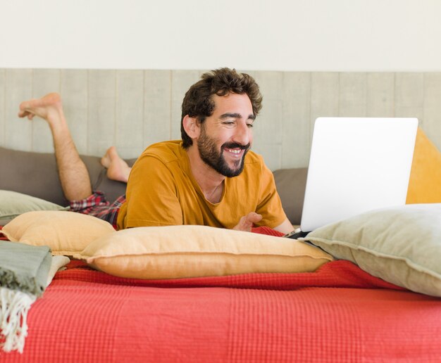 Young bearded man on a bed with a laptop