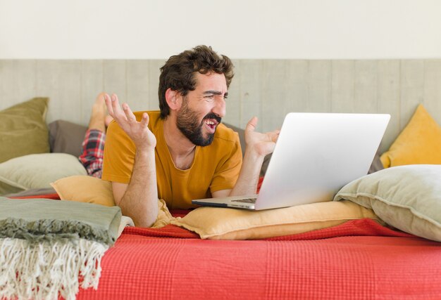 Young bearded man on a bed with a laptop