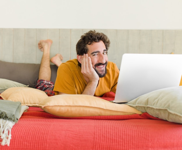 Young bearded man on a bed with a laptop