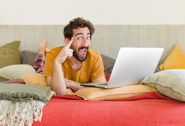 Foto giovane uomo barbuto su un letto con un laptop