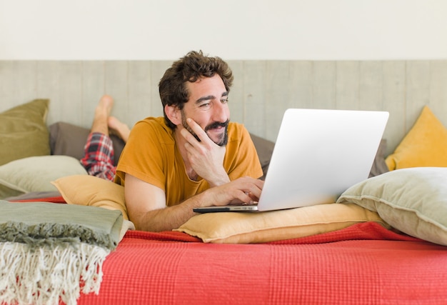 Young bearded man on a bed with a laptop