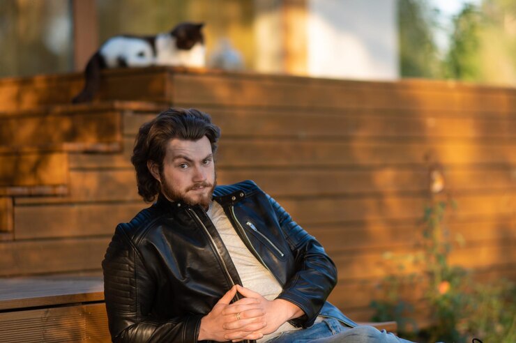 Photo young bearded man in a black leather jacket sitting on the terrace of the house