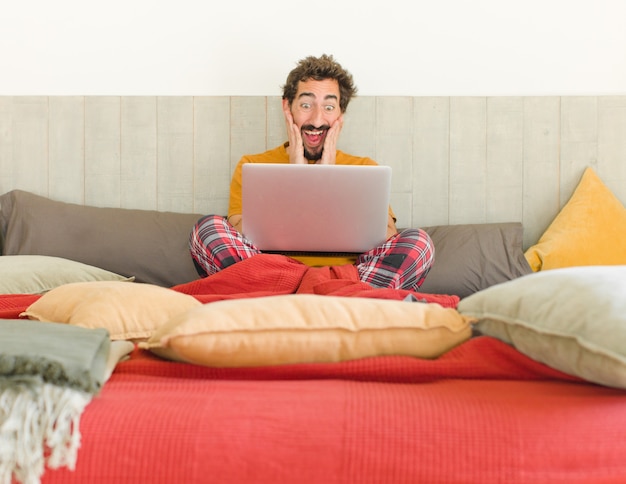 Photo young bearded man feeling happy excited and surprised looking to the side with both hands on face