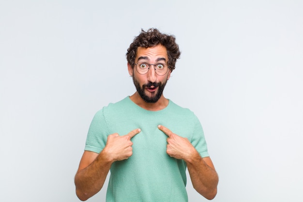Young bearded man feeling happy, surprised and proud, pointing to self with an excited, amazed look