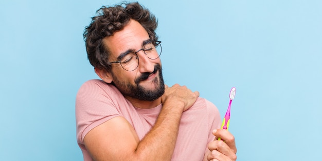 Young bearded man feeling in love and looking cute, adorable and happy, smiling romantically with hands next to face