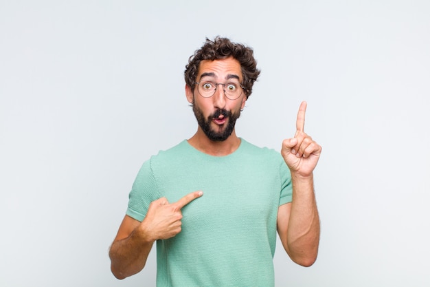 Young bearded man feeling proud and surprised, pointing to self confidently