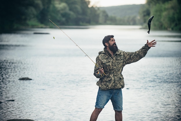 Young bearded man fishing at a lake or river flyfishing