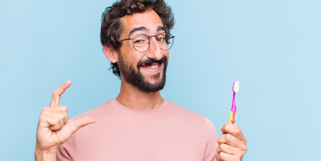 Young bearded man framing or outlining own smile with both hands, looking positive and happy, wellness concept