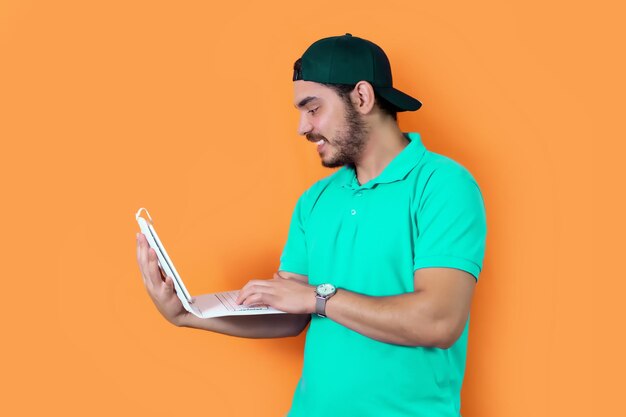 Young bearded man guy in casual tshirt used tablet posing isolated on orange background in studio