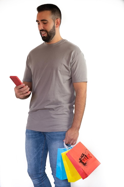 Young bearded man happily holding colorful bags and cell phone concept shopping black friday sales christmas