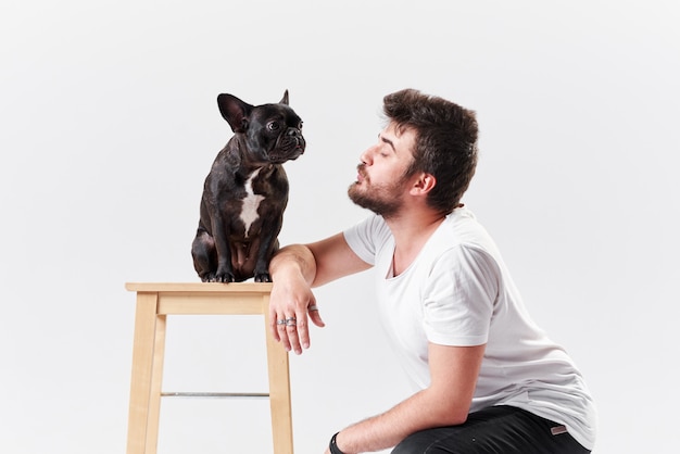 Young bearded man is training a dog, french bulldog puppy.