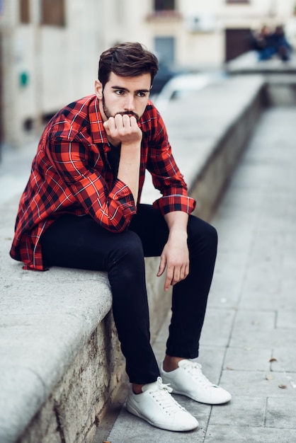 Young bearded man, model of fashion, in urban background wearing casual clothes.