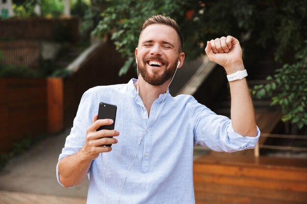 Young bearded man outdoors listening music